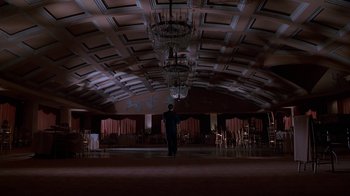Movie still from “The Shadow” (1994), directed by Russell Mulcahy – A man standing in the middle of an empty room; Extreme Wide shot, Low angle