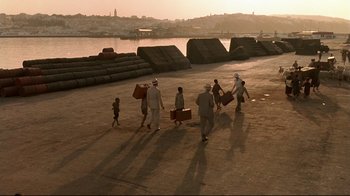 Movie still from “The Sheltering Sky” (1990), directed by Bernardo Bertolucci – A group of people walking across a dock carrying suitcases; Extreme Wide shot, High angle