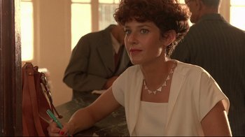 Movie still from “The Sheltering Sky” (1990), directed by Bernardo Bertolucci – A woman sitting at a table with a pen in her hand; Close Up shot, Low angle