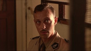 Movie still from “The Sheltering Sky” (1990), directed by Bernardo Bertolucci – A person wearing a uniform; Close Up shot, Low angle