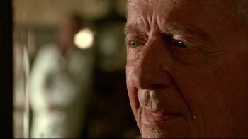 Movie still from “The Sheltering Sky” (1990), directed by Bernardo Bertolucci – An old man with a beard and blue eyes looking at the camera; Close Up shot, Over the shoulder angle