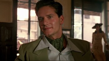 Movie still from “The Sheltering Sky” (1990), directed by Bernardo Bertolucci – A person wearing a suit and tie; Close Up shot, Low angle