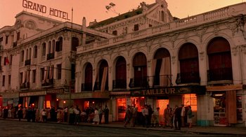 Movie still from “The Sheltering Sky” (1990), directed by Bernardo Bertolucci – A group of people standing outside of a building at night; Extreme Wide shot, Low angle