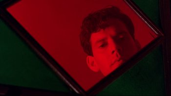 Movie still from “The Sheltering Sky” (1990), directed by Bernardo Bertolucci – A man's reflection in a red mirror; Extreme Close Up shot, Low angle