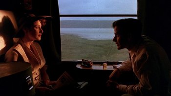Movie still from “The Sheltering Sky” (1990), directed by Bernardo Bertolucci – A man and a woman sitting in front of an open window; Medium shot, High angle