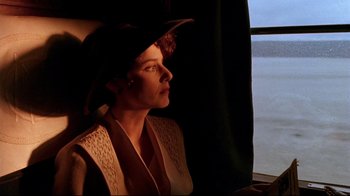 Movie still from “The Sheltering Sky” (1990), directed by Bernardo Bertolucci – A woman wearing a hat looking out of a window; Close Up shot, Low angle