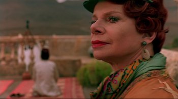 Movie still from “The Sheltering Sky” (1990), directed by Bernardo Bertolucci – An older woman wearing a green hat and a colorful scarf; Close Up shot, Low angle