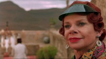 Movie still from “The Sheltering Sky” (1990), directed by Bernardo Bertolucci – An older woman wearing a green hat and red hair; Close Up shot, Low angle