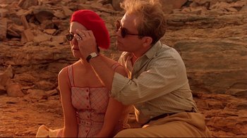 Movie still from “The Sheltering Sky” (1990), directed by Bernardo Bertolucci – A man and a woman sitting next to each other on the beach; Medium shot, Over the shoulder angle