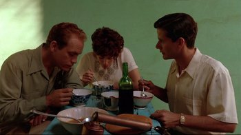 Movie still from “The Sheltering Sky” (1990), directed by Bernardo Bertolucci – A group of people sitting at a table eating food; Medium shot, High angle