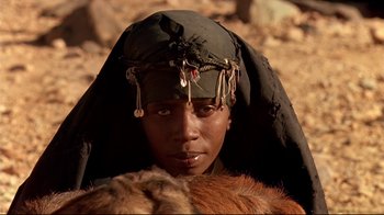 Movie still from “The Sheltering Sky” (1990), directed by Bernardo Bertolucci – A person wearing a headdress and a fur coat; Close Up shot, Low angle