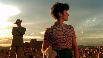 Movie still from “The Sheltering Sky” (1990), directed by Bernardo Bertolucci – A woman standing in front of an old building; Wide shot, Low angle