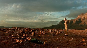 Movie still from “The Sheltering Sky” (1990), directed by Bernardo Bertolucci – A man standing in a field with a ball in his hand; Extreme Wide shot, Low angle