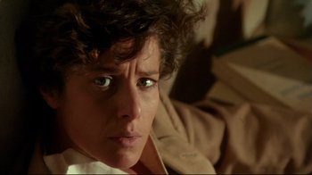 Movie still from “The Sheltering Sky” (1990), directed by Bernardo Bertolucci – A person with curly brown hair; Close Up shot, Low angle