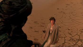 Movie still from “The Sheltering Sky” (1990), directed by Bernardo Bertolucci – A woman standing in the middle of a desert; Wide shot, High angle