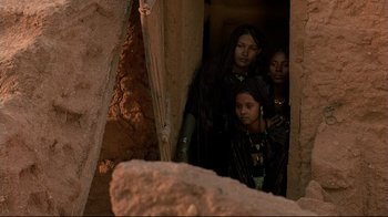 Movie still from “The Sheltering Sky” (1990), directed by Bernardo Bertolucci – A group of people standing in a room; Medium shot, Low angle