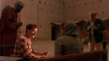 Movie still from “The Sheltering Sky” (1990), directed by Bernardo Bertolucci – A man and a woman sitting on a bench; Medium shot, Over the shoulder angle