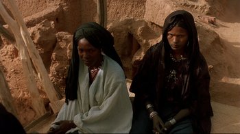 Movie still from “The Sheltering Sky” (1990), directed by Bernardo Bertolucci – A couple of women sitting next to each other on a bench; Medium shot, High angle
