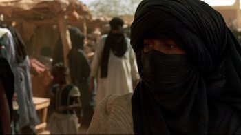 Movie still from “The Sheltering Sky” (1990), directed by Bernardo Bertolucci – A man with a black scarf on his head; Close Up shot, Over the shoulder angle