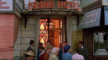 Movie still from “The Sheltering Sky” (1990), directed by Bernardo Bertolucci – A group of people standing in front of a building; Wide shot, High angle