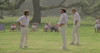 Movie still from “The Shout” (1978), directed by Jerzy Skolimowski – A group of men standing on top of a lush green field; Wide shot, Low angle