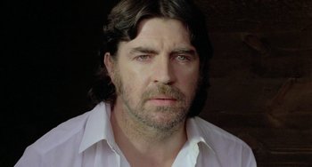 Movie still from “The Shout” (1978), directed by Jerzy Skolimowski – A person wearing a white shirt; Close Up shot, Low angle