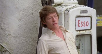 Movie still from “The Shout” (1978), directed by Jerzy Skolimowski – A man in a white shirt leaning against a white truck; Close Up shot, Low angle