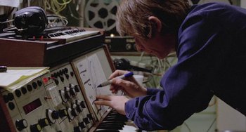 Movie still from “The Shout” (1978), directed by Jerzy Skolimowski – A man working on an electronic instrument in a recording studio; Medium shot, Overhead angle