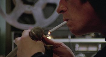 Movie still from “The Shout” (1978), directed by Jerzy Skolimowski – A man lighting a cigarette with a microphone in front of him; Extreme Close Up shot, Low angle