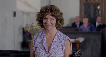 Movie still from “The Shout” (1978), directed by Jerzy Skolimowski – A woman in a purple dress smiling for the camera; Close Up shot, Low angle