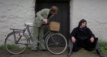 Movie still from “The Shout” (1978), directed by Jerzy Skolimowski – Two people sitting on the side of a building next to a bicycle; Wide shot, High angle