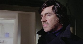 Movie still from “The Shout” (1978), directed by Jerzy Skolimowski – A person wearing a coat; Close Up shot, Low angle