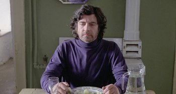 Movie still from “The Shout” (1978), directed by Jerzy Skolimowski – A man sitting at a table with a plate of food in front of him; Medium shot, Low angle