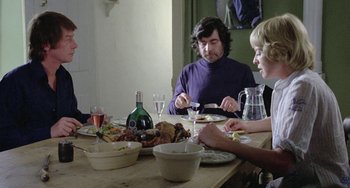 Movie still from “The Shout” (1978), directed by Jerzy Skolimowski – A group of people sitting at a dinner table; Medium shot, Over the shoulder angle