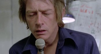 Movie still from “The Shout” (1978), directed by Jerzy Skolimowski – A person holding a microphone; Close Up shot, Low angle