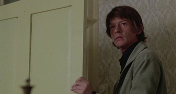 Movie still from “The Shout” (1978), directed by Jerzy Skolimowski – A man standing in front of a white door; Close Up shot, Low angle
