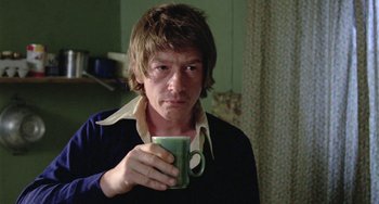 Movie still from “The Shout” (1978), directed by Jerzy Skolimowski – A man holding a green mug in his hand; Close Up shot, Over the shoulder angle