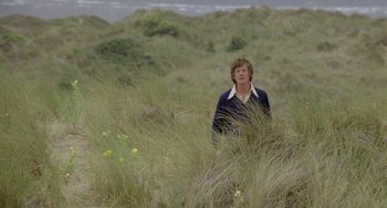 Movie still from “The Shout” (1978), directed by Jerzy Skolimowski – A man standing in a field of tall grass; Wide shot, Low angle