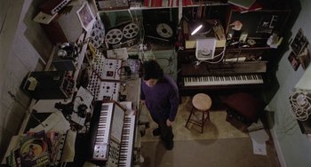 Movie still from “The Shout” (1978), directed by Jerzy Skolimowski – A man standing in front of a bunch of keyboards; Wide shot, Overhead angle