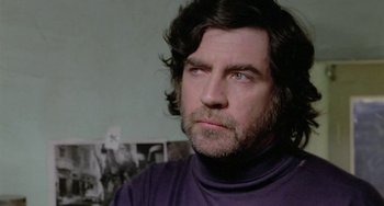 Movie still from “The Shout” (1978), directed by Jerzy Skolimowski – A person wearing a purple shirt; Close Up shot, Low angle