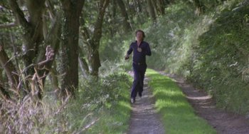 Movie still from “The Shout” (1978), directed by Jerzy Skolimowski – A woman running down a path in the woods; Wide shot, High angle
