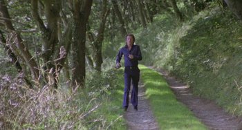 Movie still from “The Shout” (1978), directed by Jerzy Skolimowski – A woman walking down a path in the woods; Wide shot, High angle