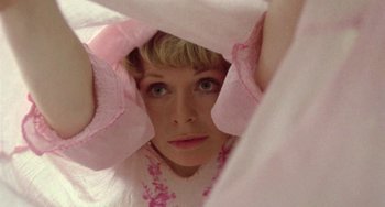 Movie still from “The Shout” (1978), directed by Jerzy Skolimowski – A woman hiding her face behind a pink sheet; Close Up shot, Overhead angle