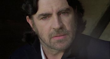 Movie still from “The Shout” (1978), directed by Jerzy Skolimowski – A person wearing a suit; Close Up shot, Low angle