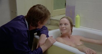 Movie still from “The Shout” (1978), directed by Jerzy Skolimowski – A woman sitting in a bath tub next to a man; Medium shot, Over the shoulder angle