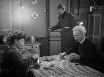 Movie still from “The Silence of the Sea” (1949), directed by Jean-Pierre Melville – A man and a woman sitting at a dining table; Medium shot, High angle
