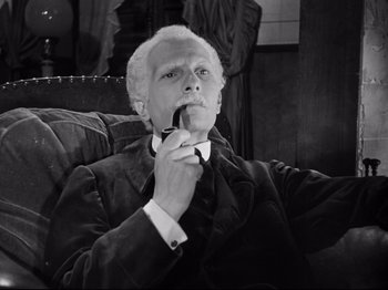Movie still from “The Silence of the Sea” (1949), directed by Jean-Pierre Melville – An older man sitting in a chair smoking a cigarette; Medium shot, High angle