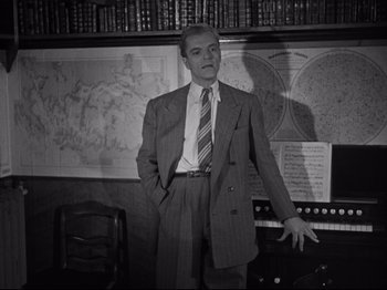 Movie still from “The Silence of the Sea” (1949), directed by Jean-Pierre Melville – A black and white photo of a man in a suit and striped tie; Medium shot, Low angle