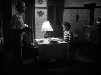 Movie still from “The Silence of the Sea” (1949), directed by Jean-Pierre Melville – A man and a woman sitting at a dinner table; Wide shot, High angle