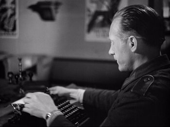Movie still from “The Silence of the Sea” (1949), directed by Jean-Pierre Melville – A black and white photo of a man using a computer; Close Up shot, Low angle